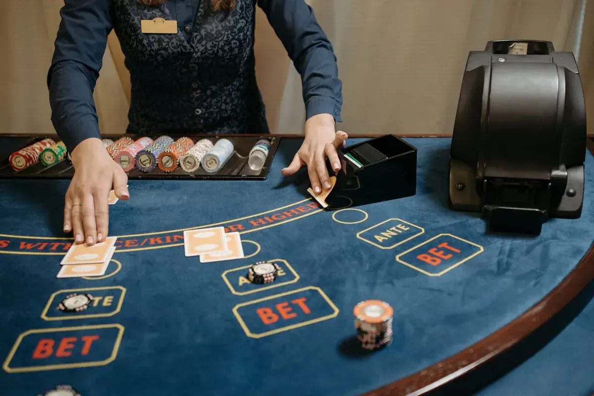 Dealer de casino en tenue devant une table de poker bleue avec jetons et cartes : vocabulaire poker en anglais